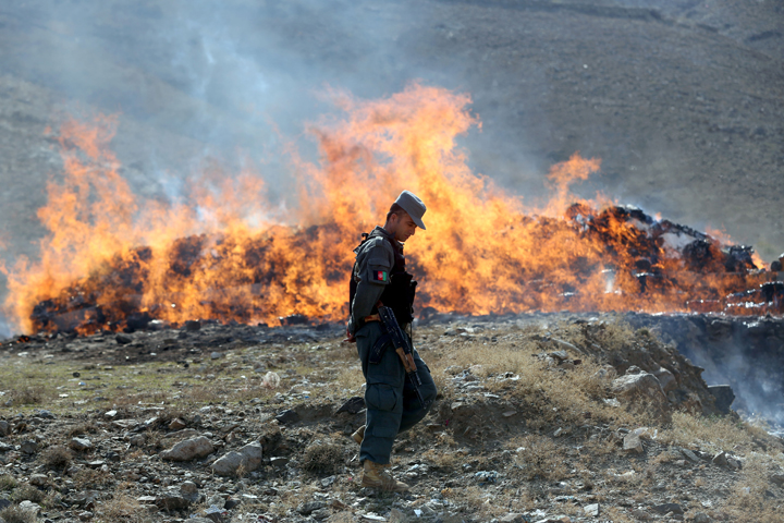 An Afghan police soldier walks past opium and narcotics set on fire during a drug burning ceremony on the outskirts of Kabul, Afghanistan, Wednesday, Oct. 29, 2014. (AP)