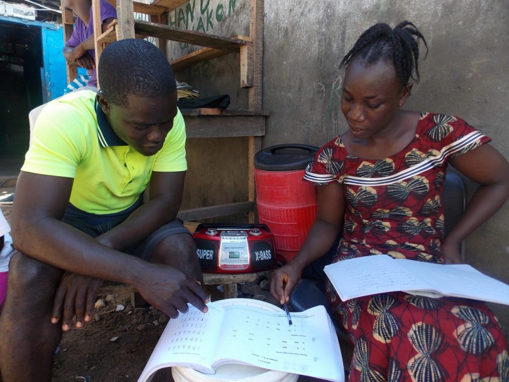 Kebbeh Sumo and her facilitator, or “study buddy,” Francis Mulbah, work on reading and writing in the EDC-USAID workbook as the class broadcasts on the radio that sits between them. In Liberia, education leaders refer to out-of-school “youth” as anyone between the ages of 13 and 35 who has never attended school or lost out on schooling, in many cases due to the long civil war.  (Courtesy EDC)