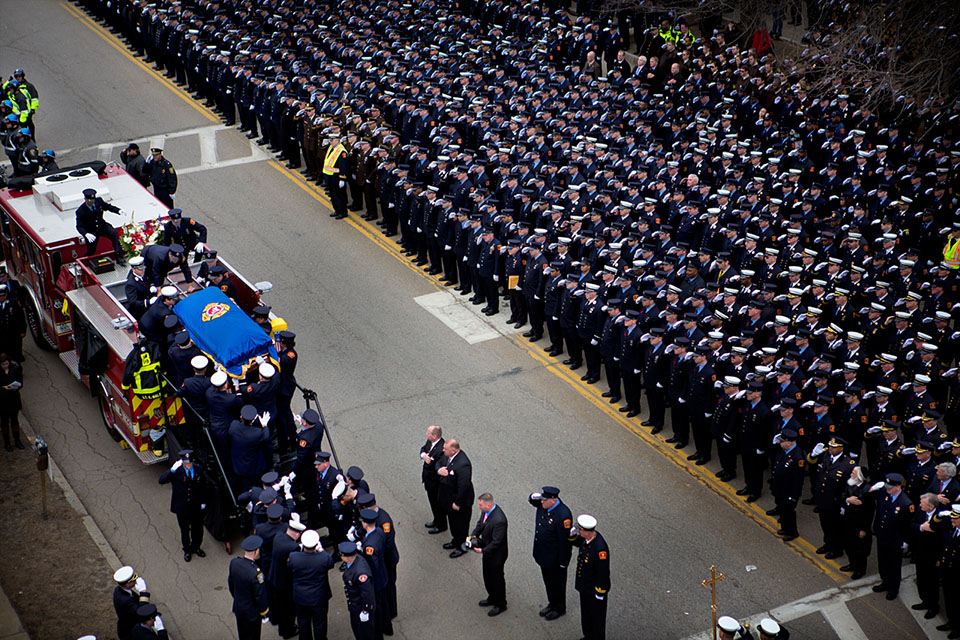 Firefighters salute as Boston Lt. Edward Walsh’s casket is removed from atop Engine 33 ahead of his funeral Mass. A similar outpouring honored fallen Firefighter Michael Kennedy. (Jesse Costa/WBUR)