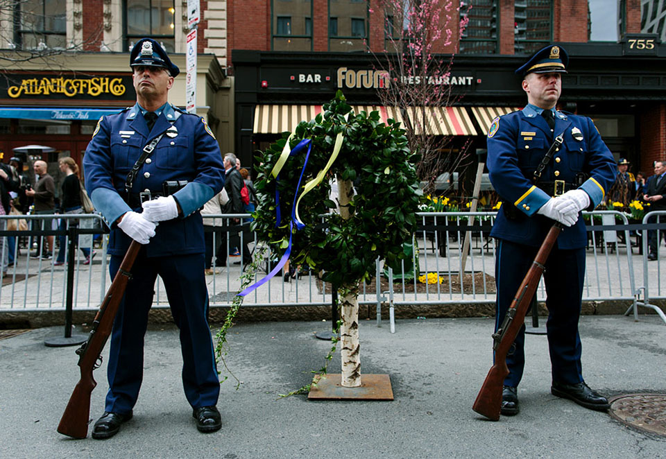 Wreaths were placed at the site of each Boston Marathon bomb blast. Here, police honor guards stand with a wreath placed outside Forum, the site where the second bomb exploded. (Joe Spurr/WBUR)