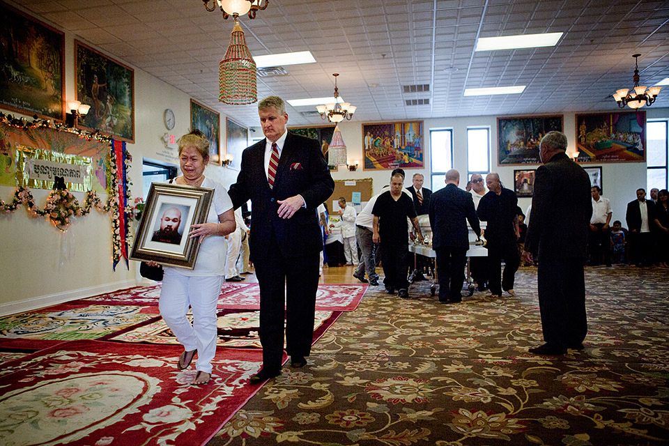 Friends and relatives gathered to remember five family members who died in a fast-moving apartment fire in Lowell on July 10. Here, Torn Sak’s mother carries a photo of her son as his casket is brought into the Glory Buddhist Temple in Lowell. (Jesse Costa/WBUR)
