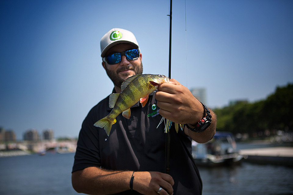 Greg Miner of Charles River Charters holds a yellow perch, our only catch during our “urban fishing” outing in the lagoons alongside the Esplanade. (Jesse Costa/WBUR)