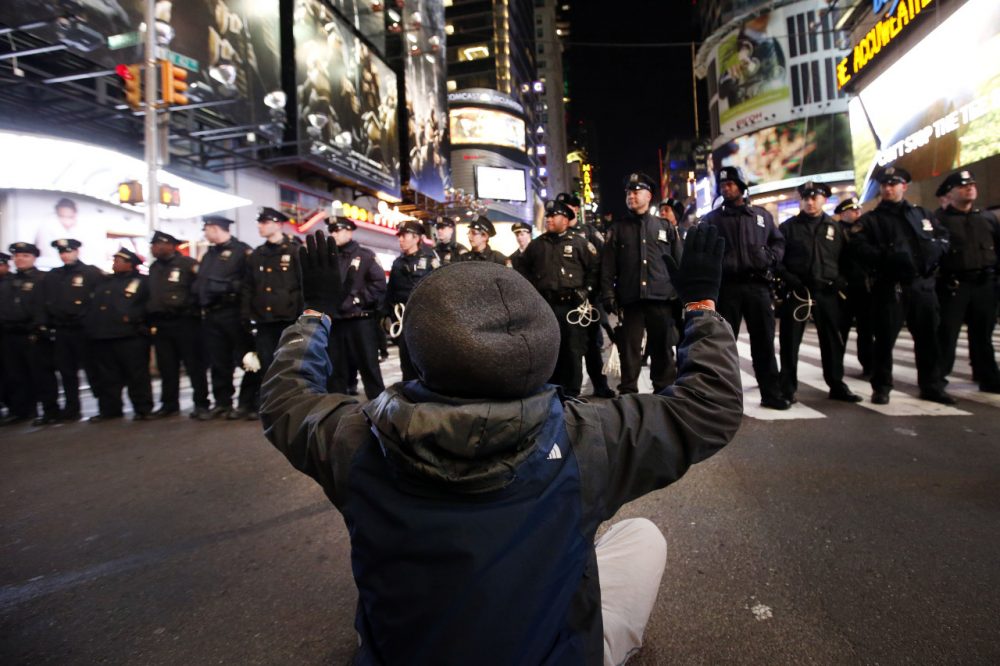 A protester sits in the road while rallying against a grand jury's decision not to indict the police officer involved in the death of Eric Garner encountering a line of police as they make their way west on 42nd Street near Times Square, Thursday, Dec. 4, 2014, in New York. (Jason DeCrow/AP)
