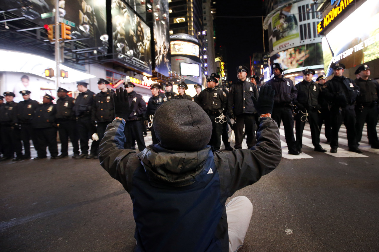 A protester sits in the road while rallying against a grand jury's decision not to indict the police officer involved in the death of Eric Garner encountering a line of police as they make their way west on 42nd Street near Times Square, Thursday, Dec. 4, 2014, in New York. (Jason DeCrow/AP)