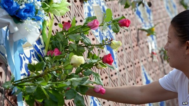 A Thai relative of a tsunami victim places roses on the Ban Nam Khem tsunami memorial park wall on the 10th anniversary of the 2004 tsunami in Phang-nga province on December 26, 2014 (AFP)