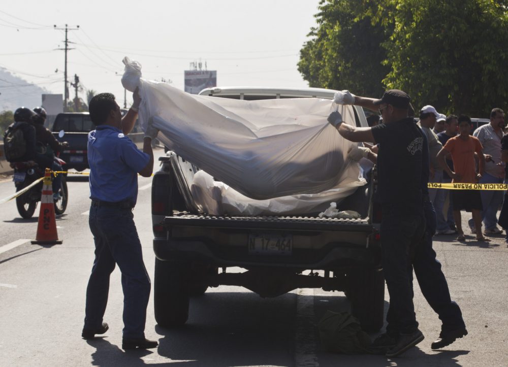 Forensic workers lift the body of an alleged gang member into the bed of a truck in San Salvador, El Salvador, on March 7, 2014. (Esteban Felix/AP)