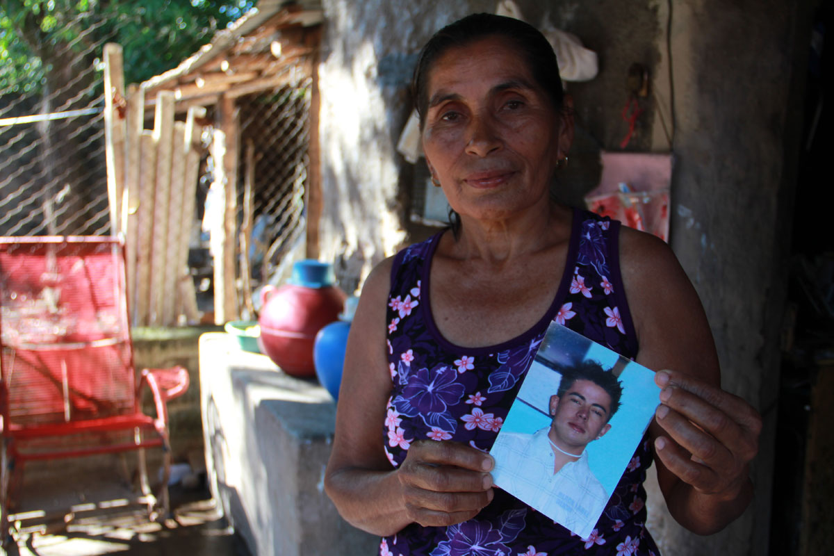 Dora, Quenia’s mom, holds a photo of her son, who lived on Nantucket. He was murdered two days after he returned to Aqua Caliente, El Salvador. (Shannon Dooling/WBUR)