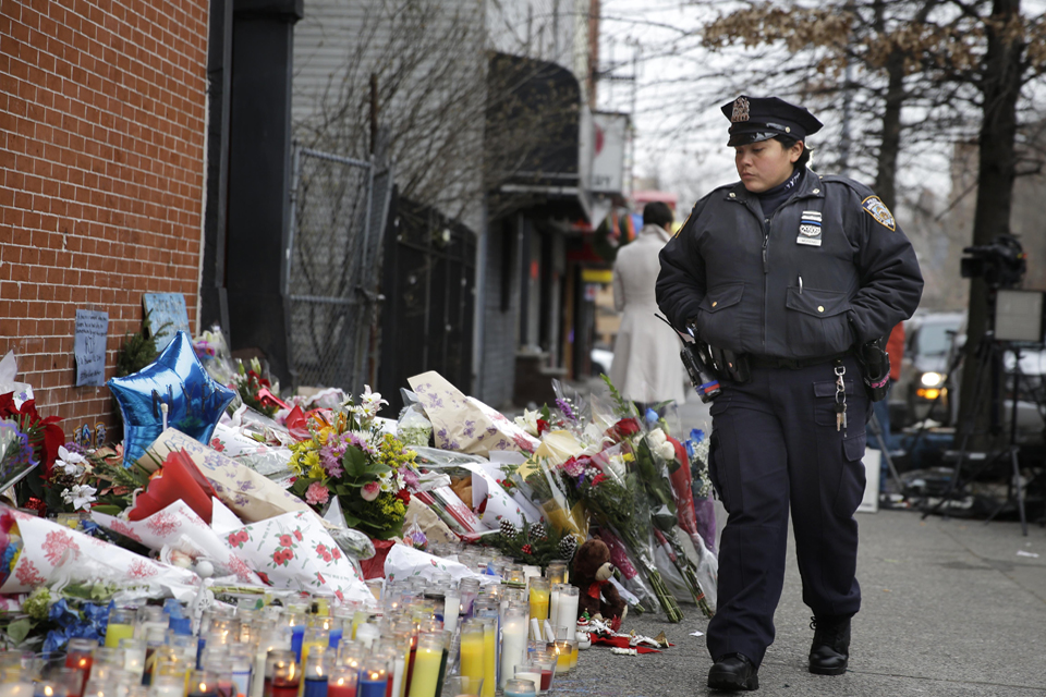 A New York City police officer looks over a makeshift memorial near the site where fellow officers Rafael Ramos and Wenjian Liu were murdered in the Brooklyn borough of New York, Monday, Dec. 22, 2014. (AP)