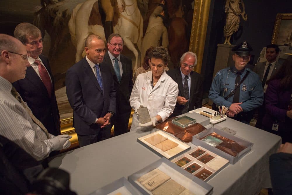 State and museum officials, including Gov. Deval Patrick and Secretary of State William Galvin, watch as Pam Hatchfield, the MFA's head of objects conservation, holds up a silver engraving found in the time capsule. (Jesse Costa/WBUR)