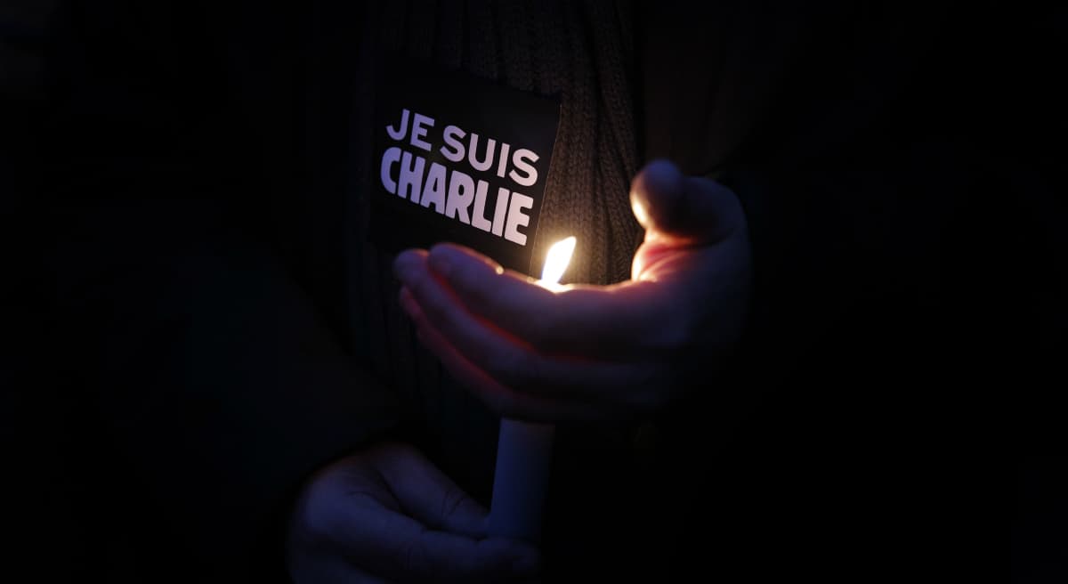 A man holds a candle and a sticker reading " I am Charlie", during a demonstration in Paris, Wednesday, Jan. 7, 2015. Three masked gunmen shouting "Allahu akbar!" stormed the Paris offices of a satirical newspaper, Charlie Hebdo, Wednesday, killing 12 people, including its editor, before escaping in a car. It was France's deadliest postwar terrorist attack. (Christophe Ena/AP)