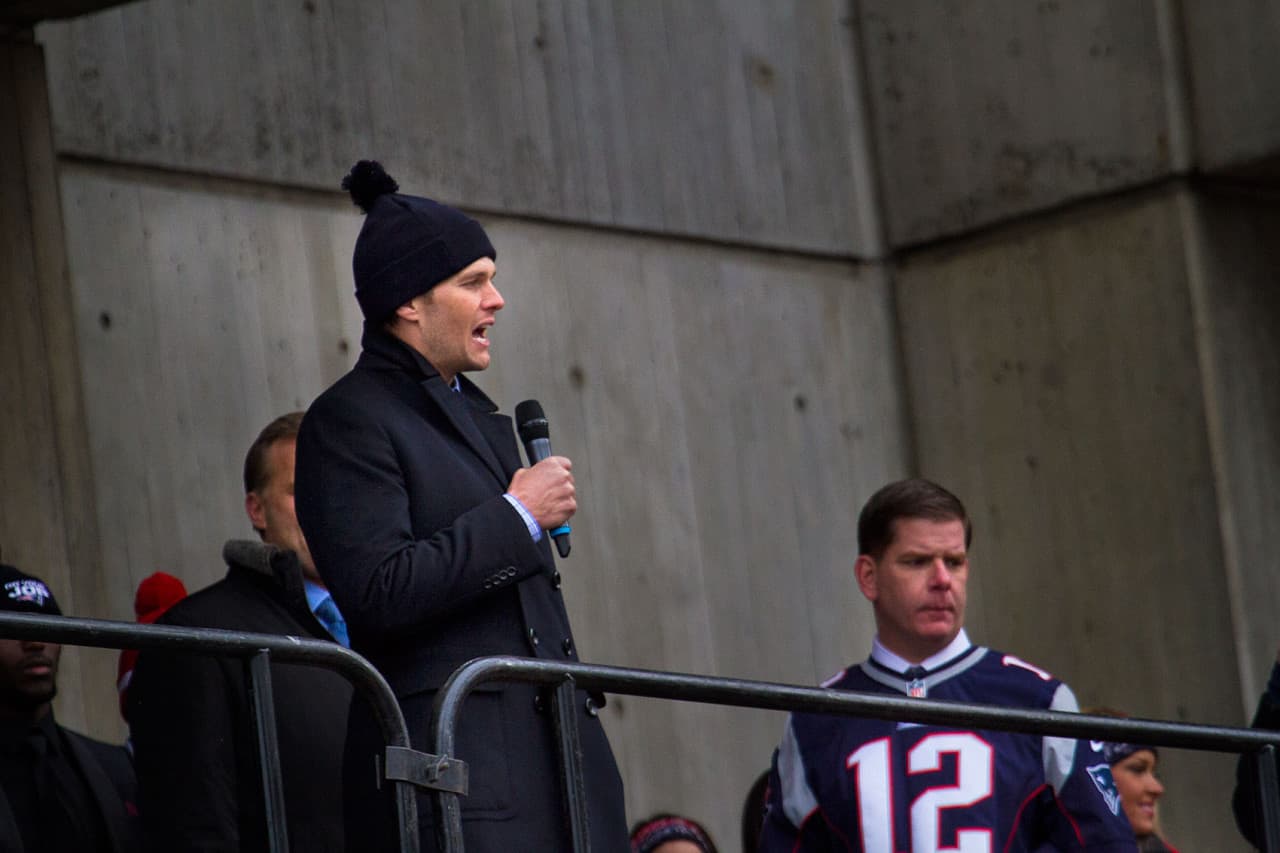 Pats quarterback Tom Brady addresses the crowd as Boston Mayor Marty Walsh (right) looks on. (Jesse Costa/WBUR)