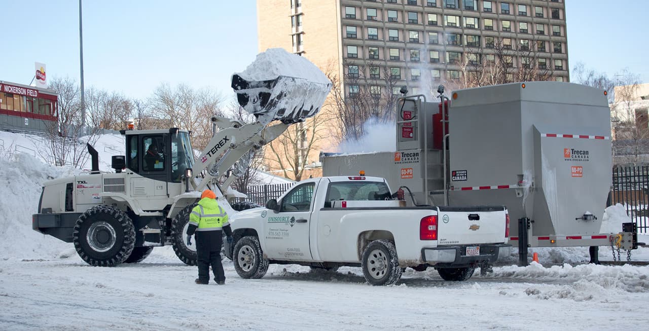 A loader piles snow into a snow melting machine on Harry Agganis Way by Boston University. (Robin Lubbock/WBUR)