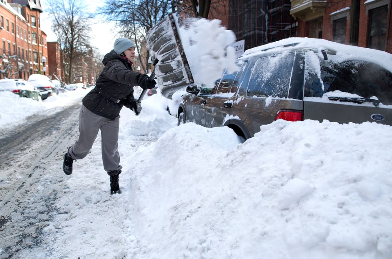 Angelica Irizarry clears the snow away from around her car on Rutland St. in the South End. (Robin Lubbock/WBUR)
