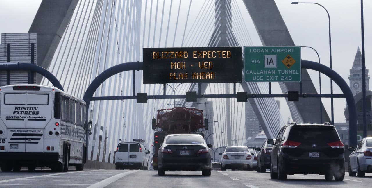 With a road sign warning of an expected blizzard, morning commuters travel across the Zakim Bridge Monday. (Charles Krupa/AP)