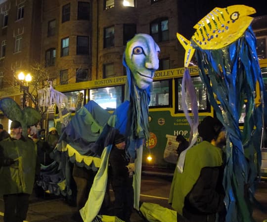 A parade puppet makes its way down the street. (Zoe Sobel/WBUR)