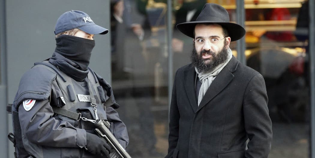 A police officer and a Jewish passerby talk outside the kosher grocery where four people were killed by Amedy Couiibaly.  (Francois Mori/AP)
