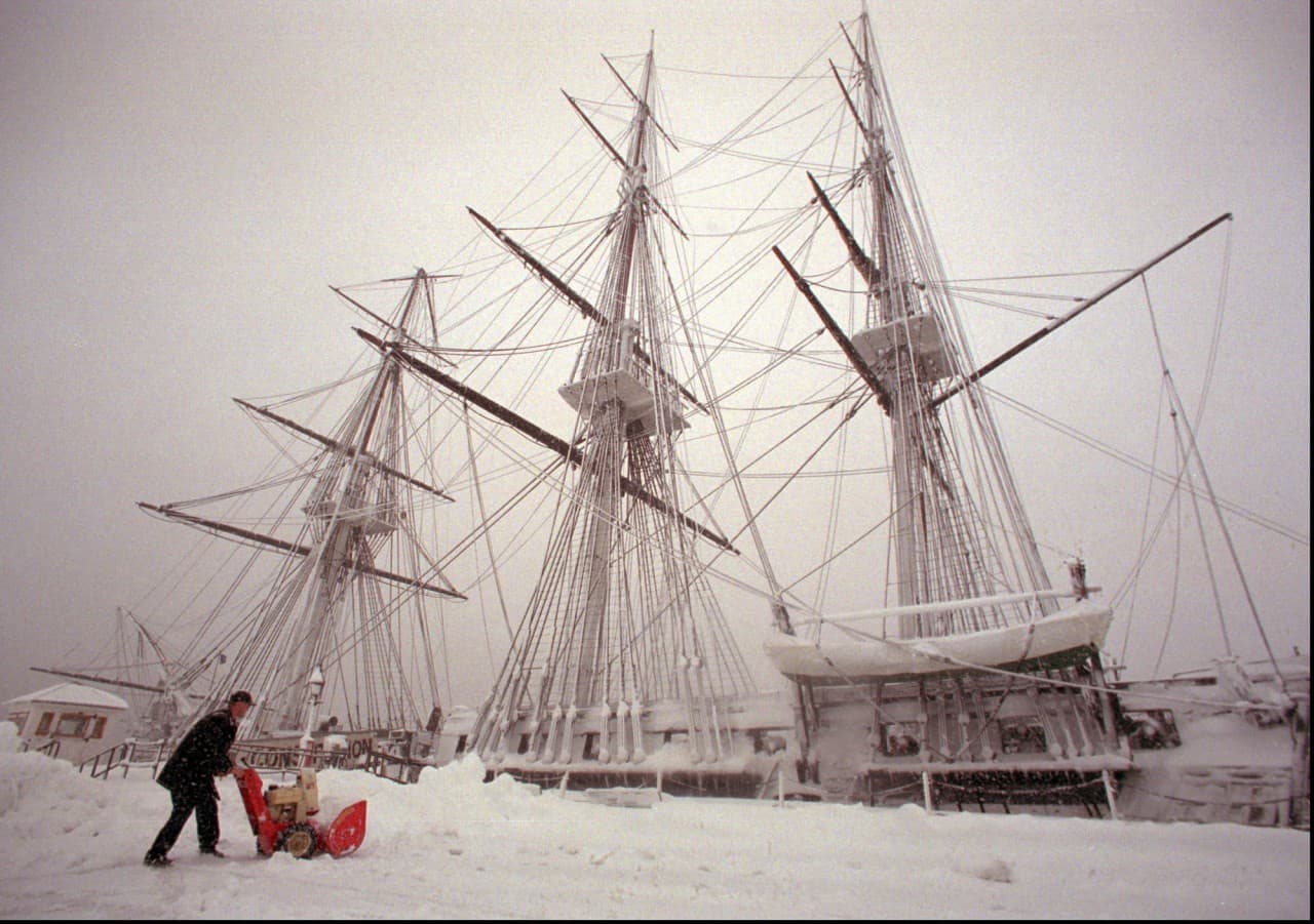 U.S. Navy MS Seaman Jared Kendall of Clark, Mo., clears the area near the snow-covered U.S.S. Constitution, the oldest commissioned Navy vessel, at the Charlestown Navy Yard in Boston, Tuesday, April 1, 1997. The top section of the ship's foremast, left, snapped Monday night during a fierce blowing snowstorm which dumped over 20 inches of snow on the Boston area. (Julia Malakie/AP)