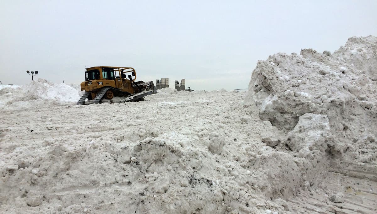 Plows move mountains of snow at Boston's biggest snow pile in the Seaport District in February 2015. The piles have melted to reveal dozens of tons of trash. (Rebecca Sananes for WBUR)