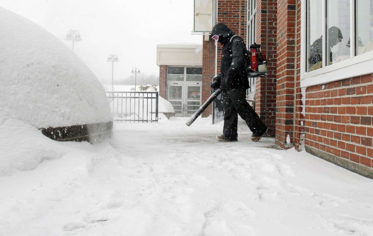 Brian Murphy uses a leaf blower to remove snow from in front of a store entryway Monday in Sudbury. (Bill Sikes/AP)