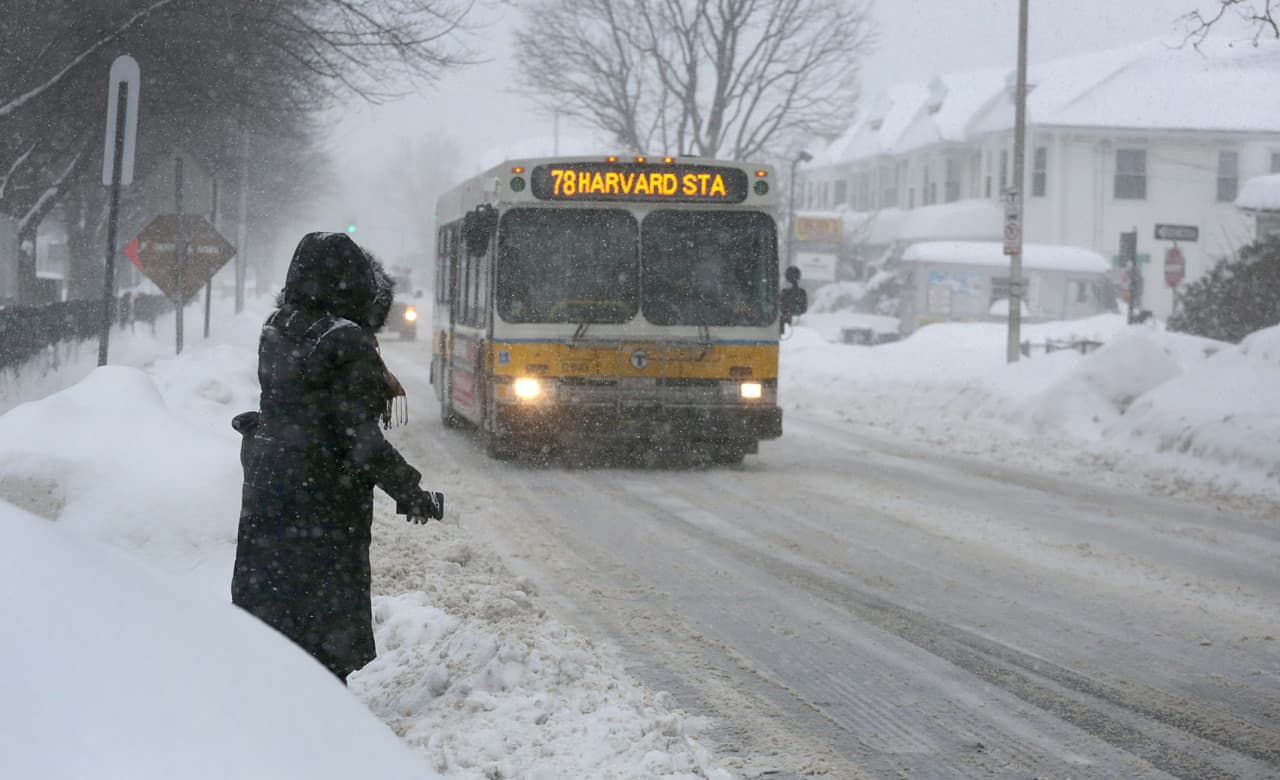 Alma Az, 43, waits for a bus on Concord Avenue in Cambridge Monday, as she makes her way to work in Copley Square. (Robin Lubbock/WBUR)