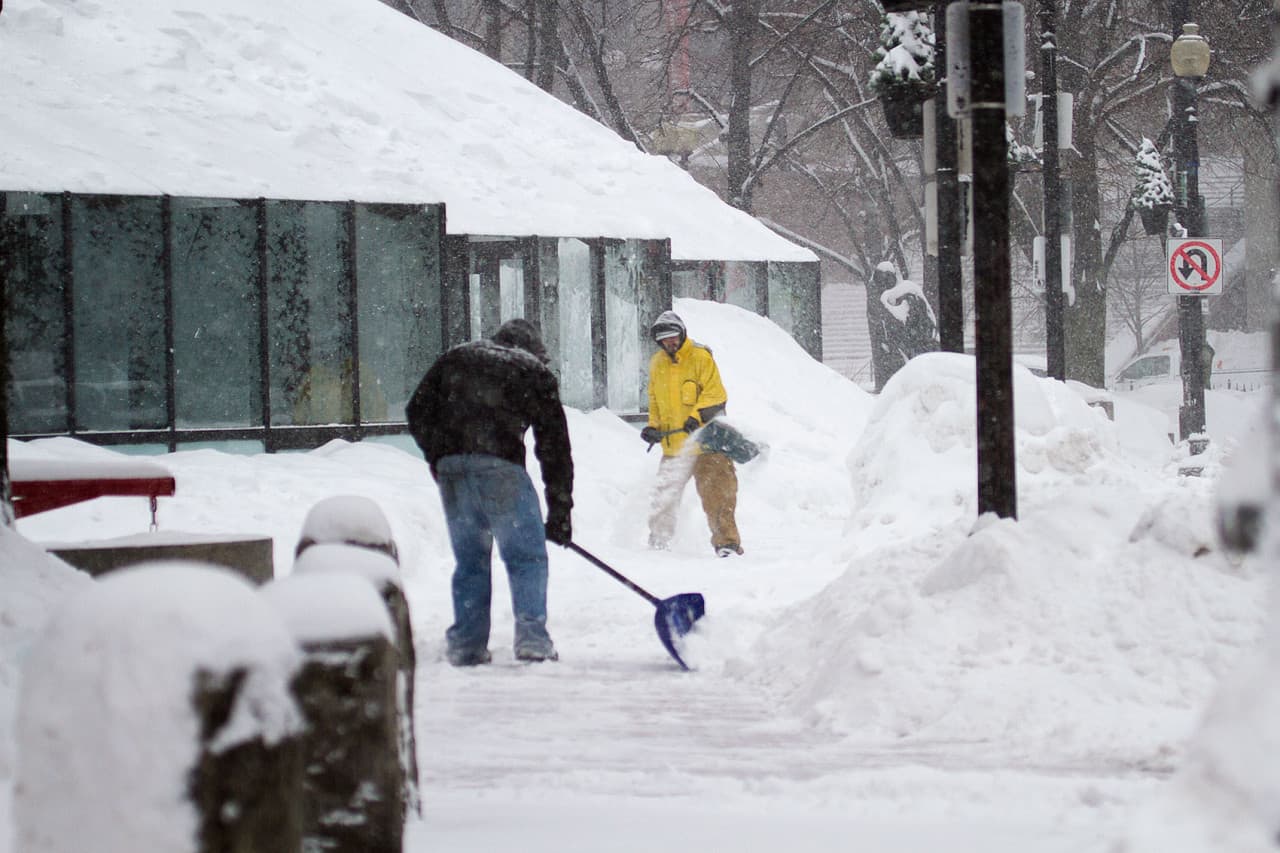 Two workers shovel the sidewalks around Faneuil Hall Monday. (Jesse Costa/WBUR)