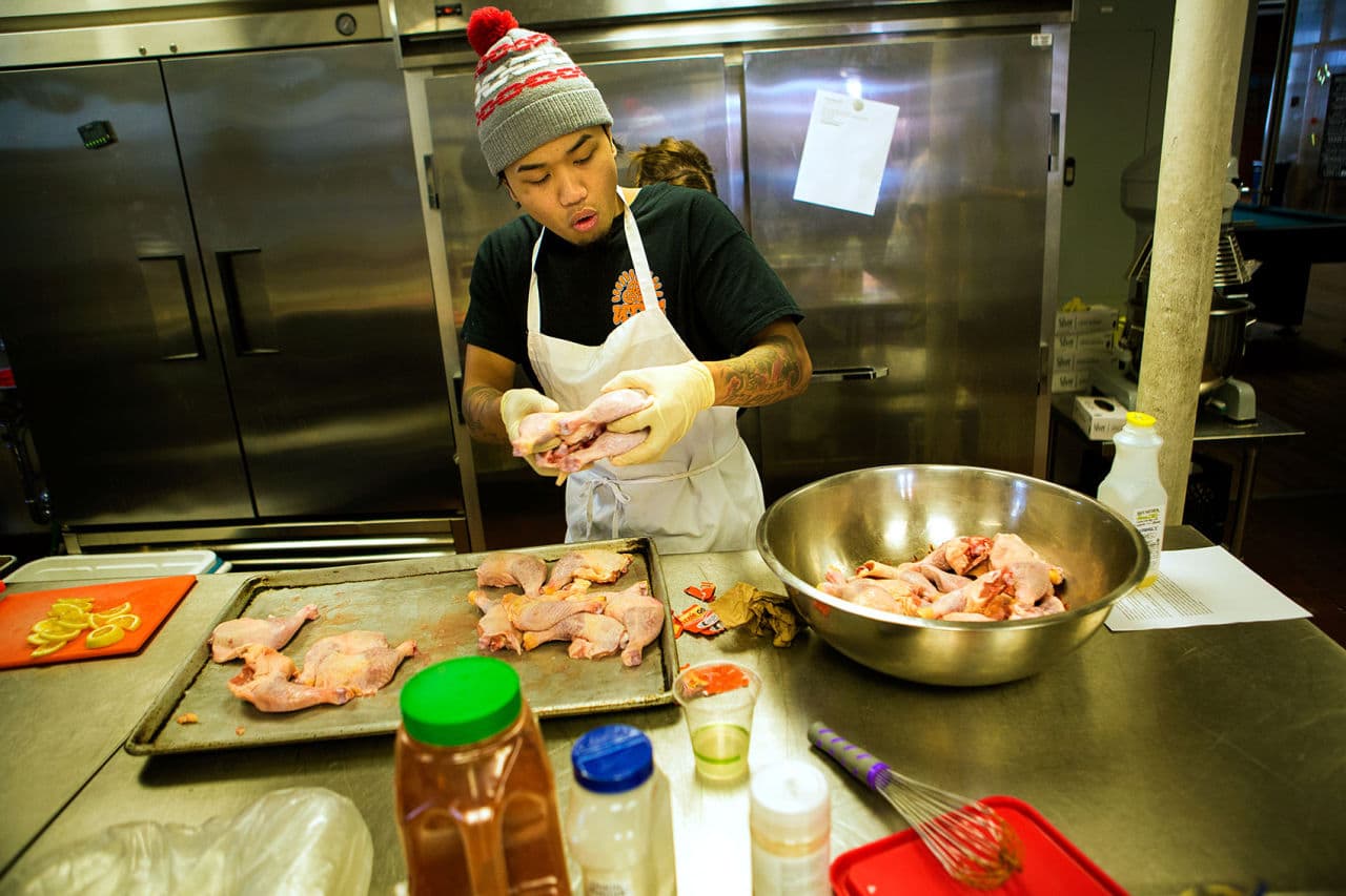 Benny Siep preparing chicken in the kitchen at Café UTEC. (Jesse Costa/WBUR)