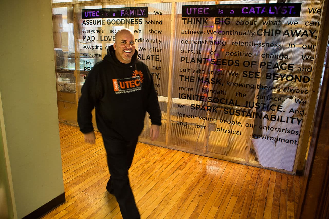 Executive Director Gregg Croteau walks through a hallway where UTEC mission statement is displayed. (Jesse Costa/WBUR)