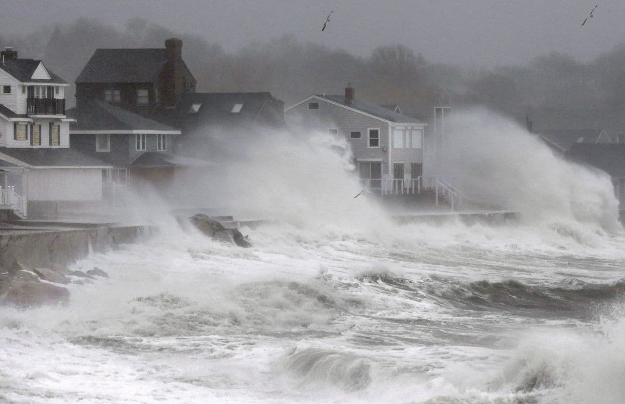Waves splash against a seawall and onto houses along the Atlantic coast in Scituate. (Steven Senne/AP)