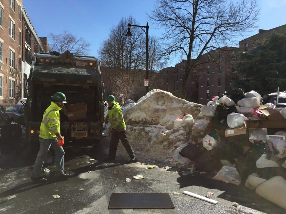 Trash collectors work through a giant pile of garbage on Hemenway Street. (Simon Rios)