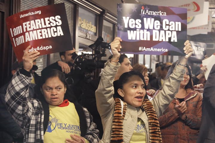 People cheer and hold up signs during a town hall forum, Tuesday, Feb. 17, 2015, in Houston. The meeting was held to help immigrants learn and prepare for President Barack Obama's immigration order in spite of an injunction from a federal judge in Texas. (AP)
