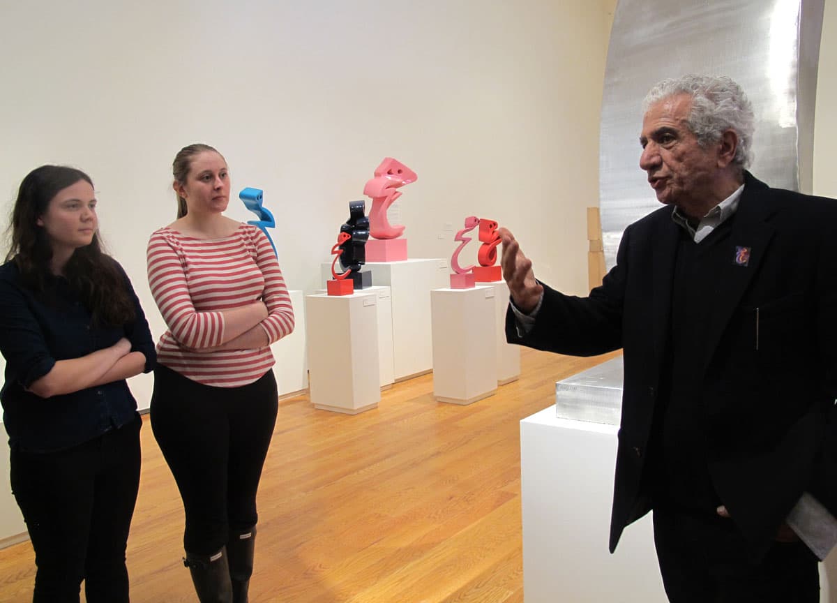 Iranian artist Parviz Tanavoli, right, talks to two Wellesley College students at the school’s Davis Museum. (Andrea Shea/WBUR)