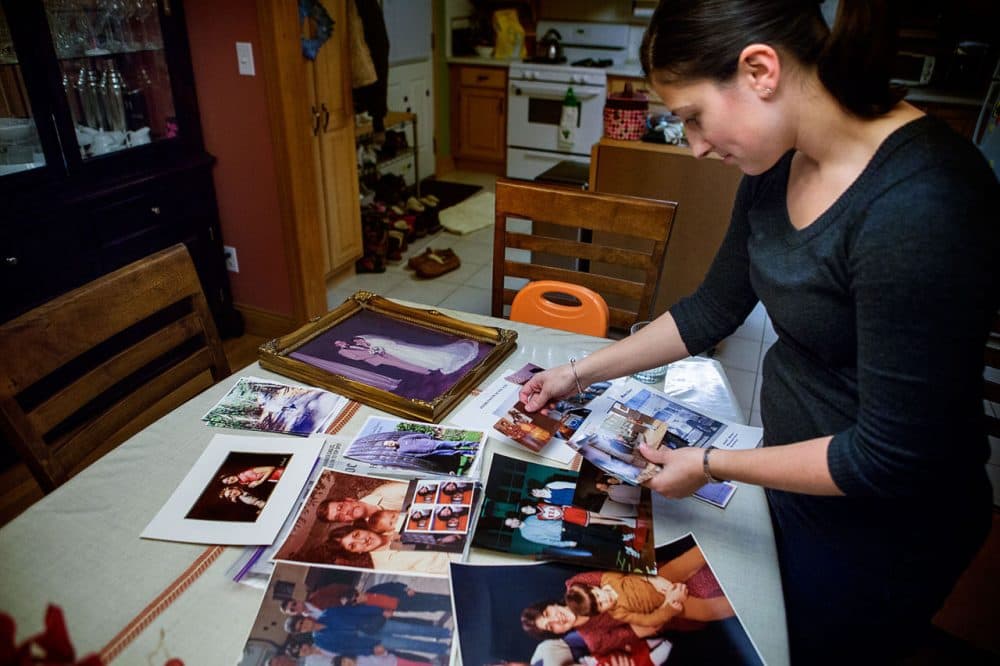 Valerie Alfeo files through a table full of family photos at her home in Waltham. Her father, Ted Washburn, took his own life in 2011. He was 54.  (Jesse Costa/WBUR)
