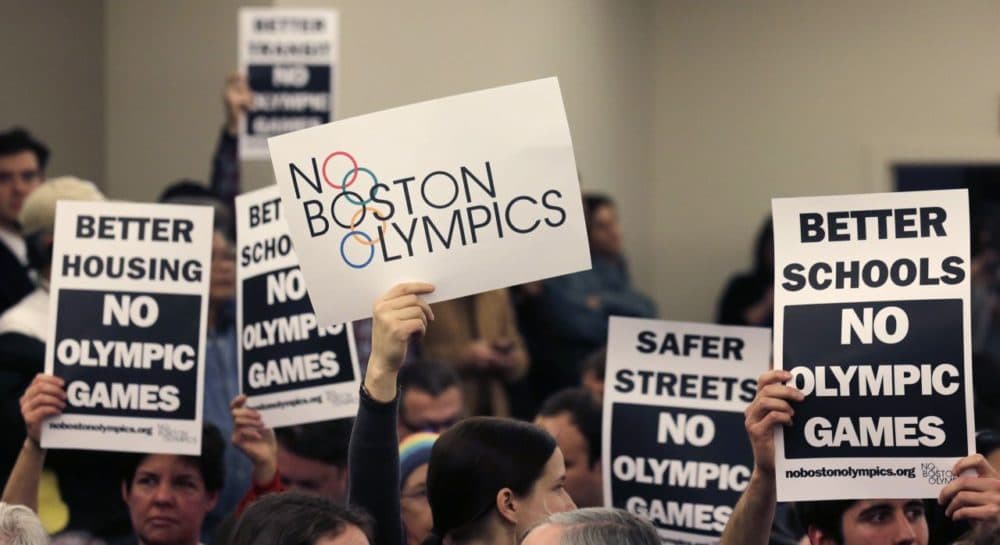 People hold up placards against bringing the Olympic Games to Boston during the first public forum regarding the city's 2024 Olympic bid in February 2015. (Charles Krupa/AP)