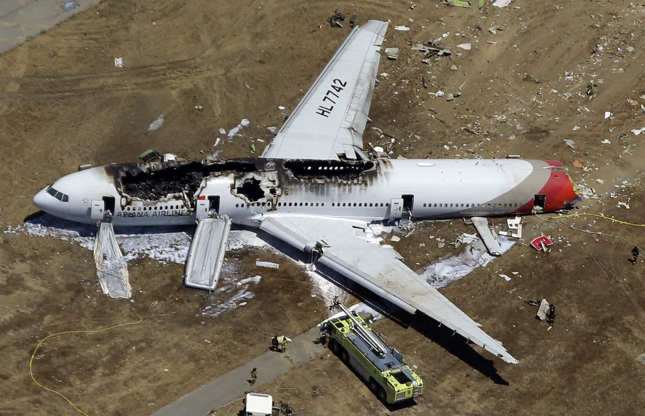 In this July 6, 2013, aerial file photo, the wreckage of Asiana Flight 214 lies on the ground after it crashed at the San Francisco International Airport in San Francisco. On Tuesday, March 3, 2015, more than 70 passengers aboard that flight reached a settlement in their lawsuits against the airline. (Marcio Jose Sanchez/AP)