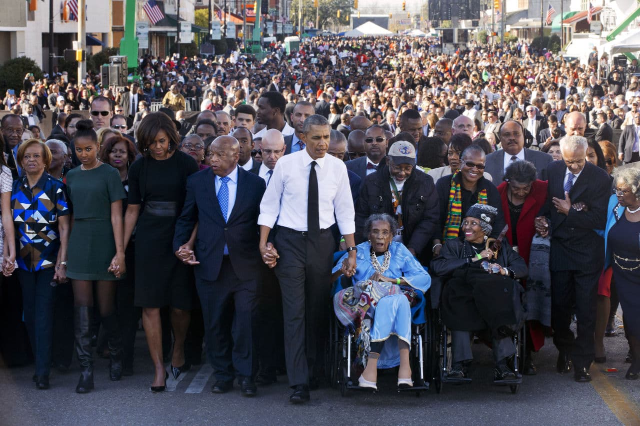 President Barack Obama, center, walks as he holds hands with Amelia Boynton Robinson, who was beaten during "Bloody Sunday," as they and the first family and others including Rep. John Lewis, D-Ga,, left of Obama, walk across the Edmund Pettus Bridge in Selma, Ala. for the 50th anniversary of “Bloody Sunday," a landmark event of the civil rights movement, Saturday, March 7, 2015. (Jacquelyn Martin/AP)