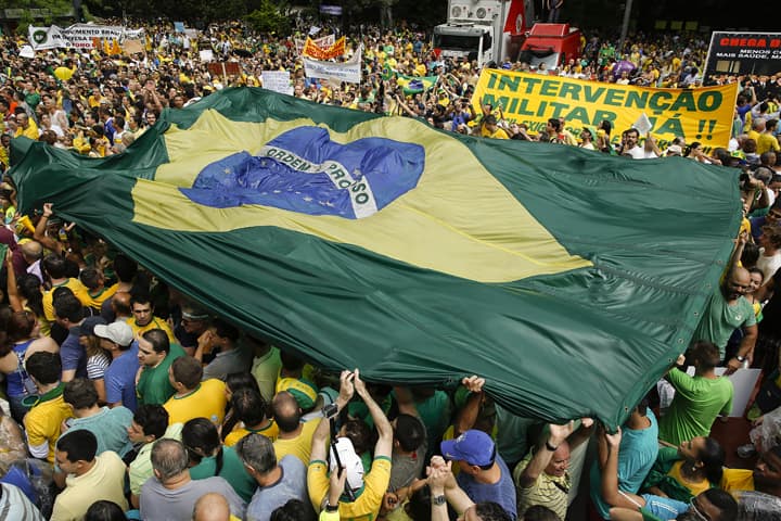 Demonstrators hold a Brazilian flag and a sign that reads in Portuguese "Military intervention now!" during a march demanding the impeachment of Brazil's President Dilma Rousseff in Sao Paulo, Brazil, Sunday, March 15, 2015. (AP)