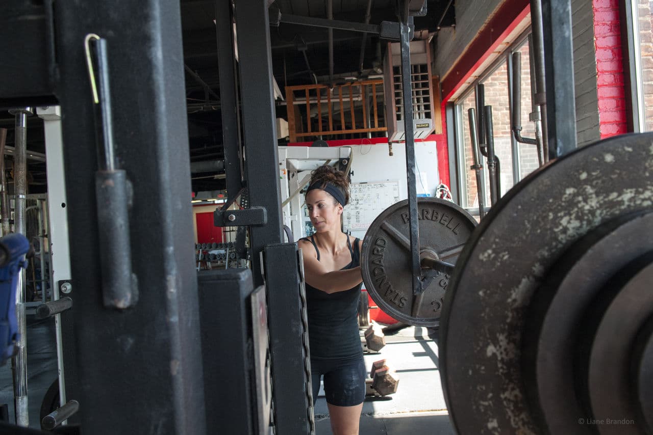 Jessica Diedrich loads weights at Total Performance Sports in Everett. (Liane Brandon)