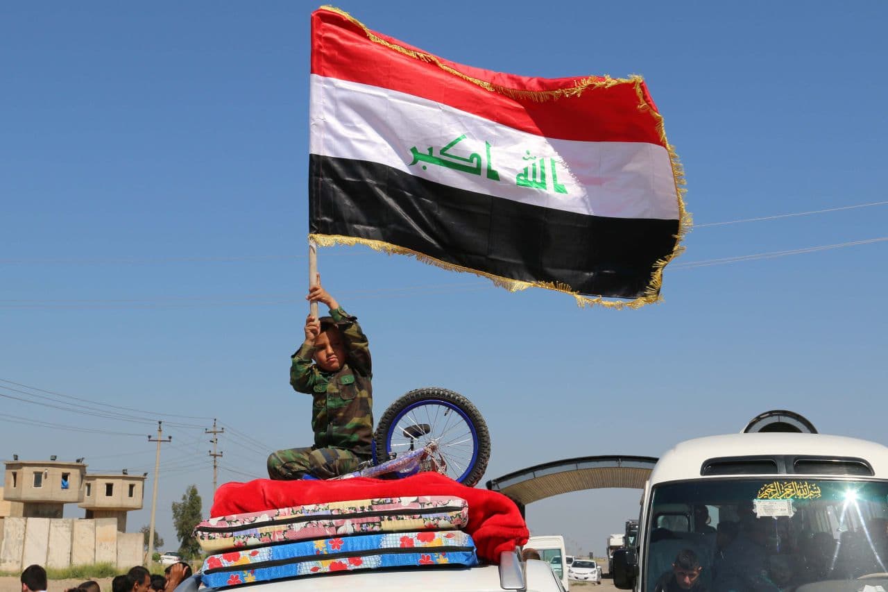 An Iraqi child waves his national flag as displaced families leave Kirkuk on April 2, 2015, to go back to the cities of Tikrit, Samara and al-Alam after they were retaken by security forces and pro-government fighters from the Islamic State group. (Marwan Ibrahim/AFP/Getty Images)