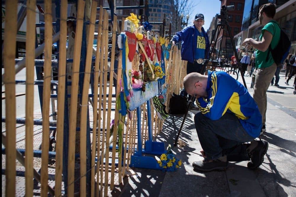 A man stops and prays for the victims of the Boston Marathon bombing Wednesday at a small memorial near the finish line on Boylston Street.(Jesse Costa/WBUR)