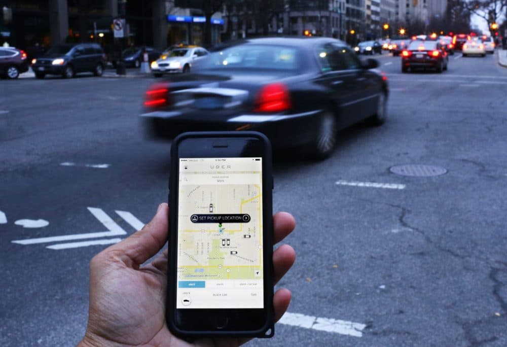 The Uber app is shown as cars drive by in Washington, D.C. on March 25, 2015. (Andrew Caballero-Reynolds/AFP/Getty Images)