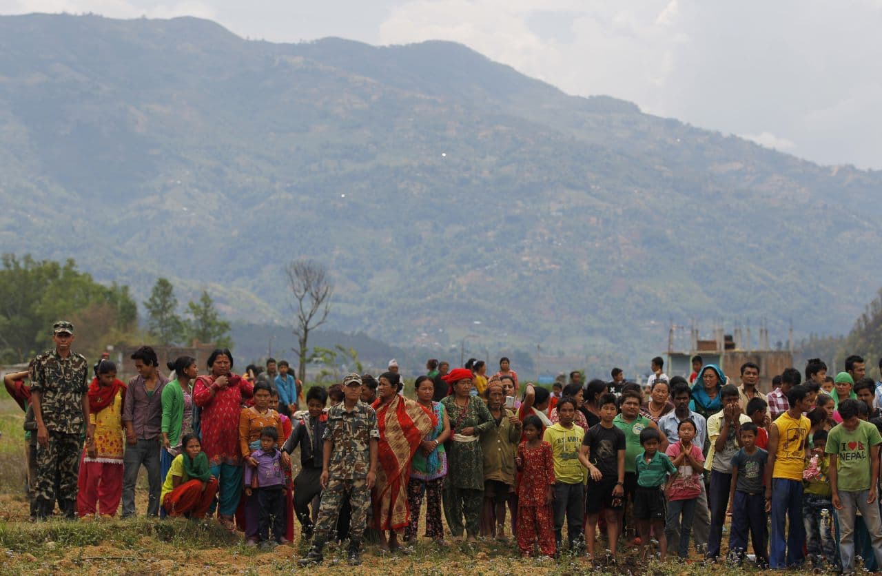 Nepalese villagers watch as relief material is brought in an Indian air force helicopter for victims of Saturday's earthquake at Trishuli Bazar in Nepal, Monday. (Altaf Qadri/AP)