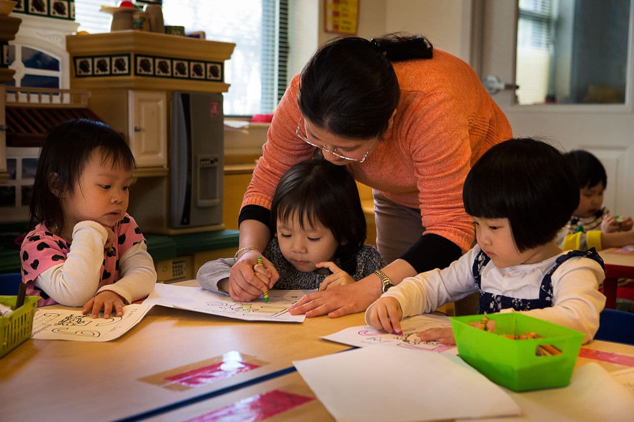 Teacher Mai Phan works on writing exercises with a child during a preschool class at the Vietnamese American Community Center in Dorchester. (Jesse Costa/WBUR)