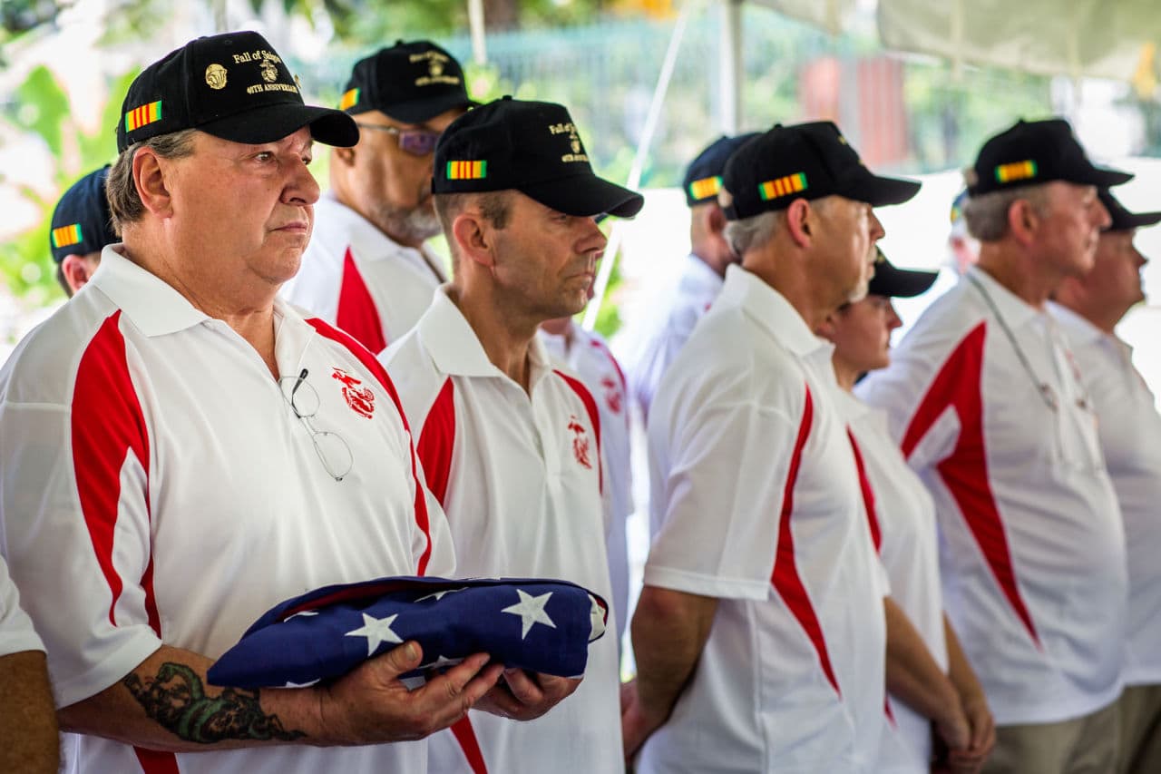 At a ceremony in Ho Chi Minh City Thursday, former Marine Security Guard John Ghilain, of Malden, holds a folded American flag in honor of one of the last two U.S. troops to die on Vietnamese soil, Cpl. Charlie McMahon, of Woburn. (Quinn Ryan Mattingly for WBUR)