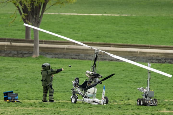A member of a bomb squad pulls something off of a small helicopter and throws it after a man landed on the West Lawn of the Capitol in Washington, Wednesday, April 15, 2015.  A Florida postal carrier named Doug Hughes took responsibility for the stunt on a website where he said he was delivering letters to all 535 members of Congress in order to draw attention to campaign finance corruption. (AP)