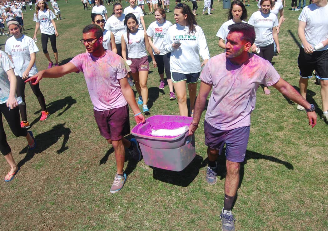 Organizers carry a tub of violet powder onto the field as they prepare to celebrate Holi. (Greg Cook)