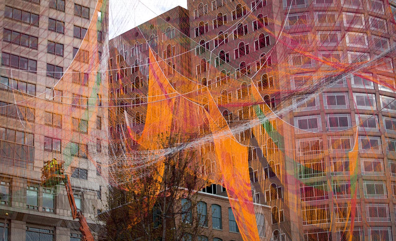 Construction workers watch from an elevated platform as Janet Echelman's sculpture takes shape. (Robin Lubbock/WBUR)
