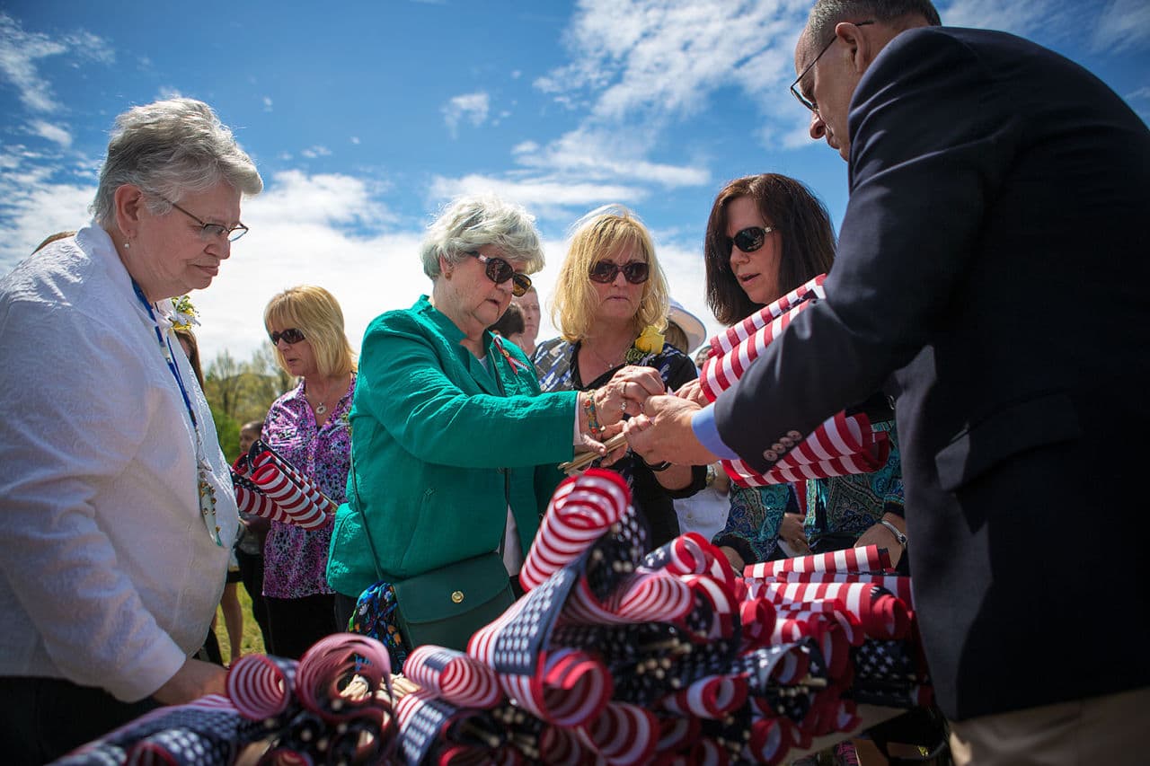 Volunteers hand out flags to be planted in honor of the fallen heroes named during the ceremony. (Jesse Costa/WBUR)