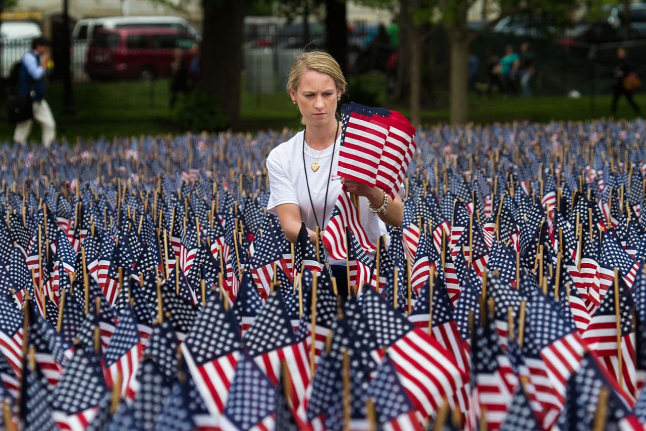Volunteer Shannon Day plants fallen flags at the foot of the Soldiers and Sailors Monument in the Boston Common. (Jesse Costa/WBUR)