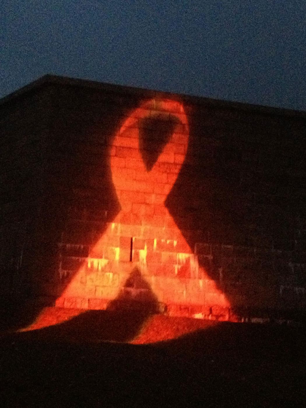 At last December’s “Medicine Wheel,” the iconic red AIDS ribbon was projected onto Fort Independence in South Boston. (Courtesy)