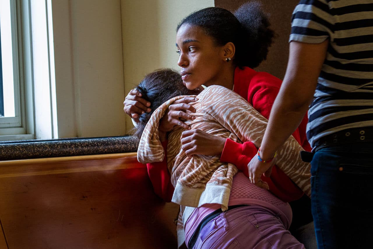 Yadielys Deleon Camacho&#039;s cousin, Julysa Cordova, holds her grieving grandmother, Maria Cruz, at Dorchester Municipal Court Monday after an outburst she had during the arraignment of James Horton. (Jesse Costa/WBUR)
